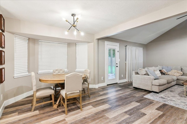 dining area featuring hardwood / wood-style flooring, vaulted ceiling, a textured ceiling, and a chandelier