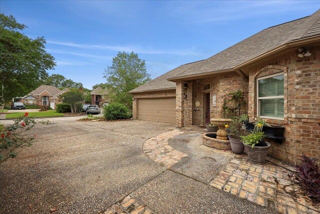 11 Regency Pl, Orange, TX 77630 - view of property exterior featuring driveway, a shingled roof, an attached garage, and brick siding