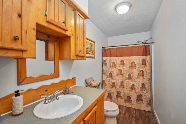 bathroom featuring a shower with shower curtain, vanity, a textured ceiling, hardwood / wood-style floors, and toilet