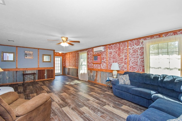 living room featuring ceiling fan, ornamental molding, a wall mounted AC, wood walls, and hardwood / wood-style flooring