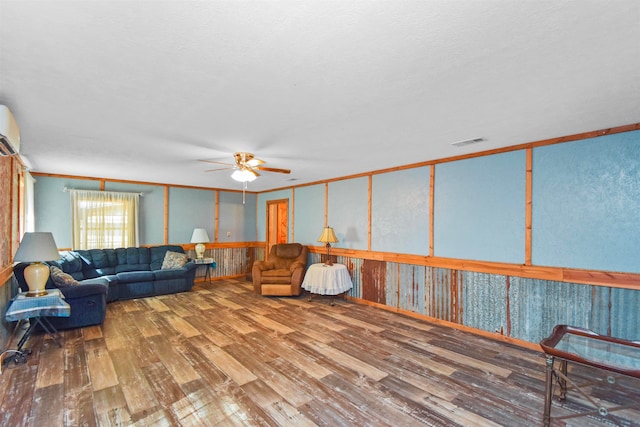 living room with hardwood / wood-style floors, ceiling fan, a wall mounted air conditioner, and crown molding