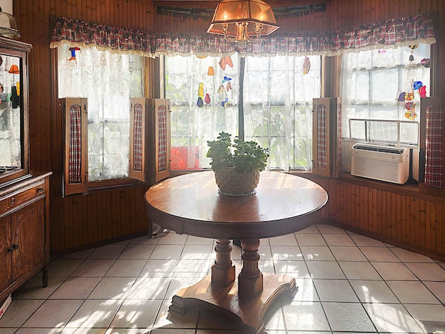 tiled dining area with cooling unit, a wealth of natural light, and wooden walls