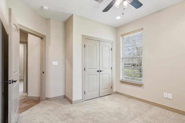 unfurnished bedroom featuring baseboards, ceiling fan, a closet, and carpet floors