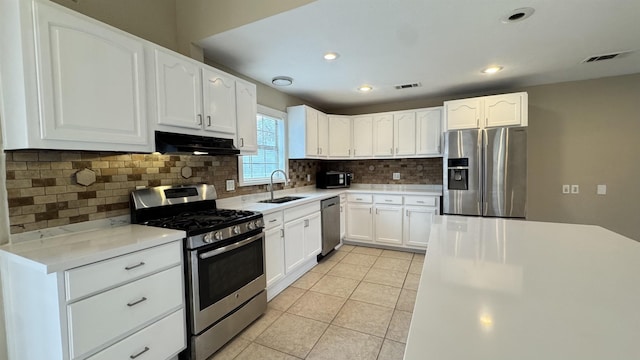 kitchen with sink, tasteful backsplash, light tile patterned floors, appliances with stainless steel finishes, and white cabinets