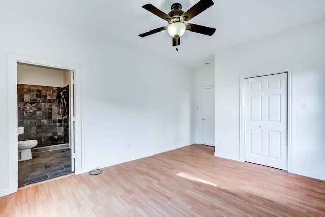 unfurnished bedroom featuring ceiling fan, ensuite bath, a closet, and light hardwood / wood-style flooring