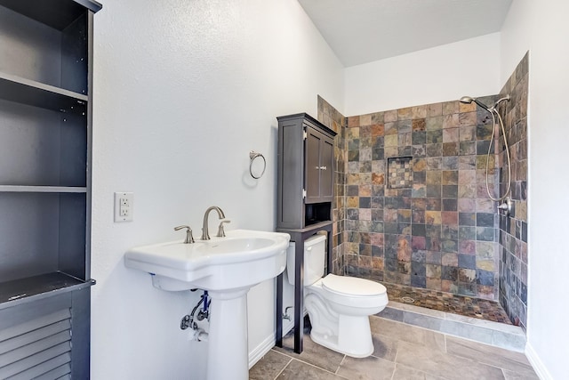 bathroom with a tile shower and toilet