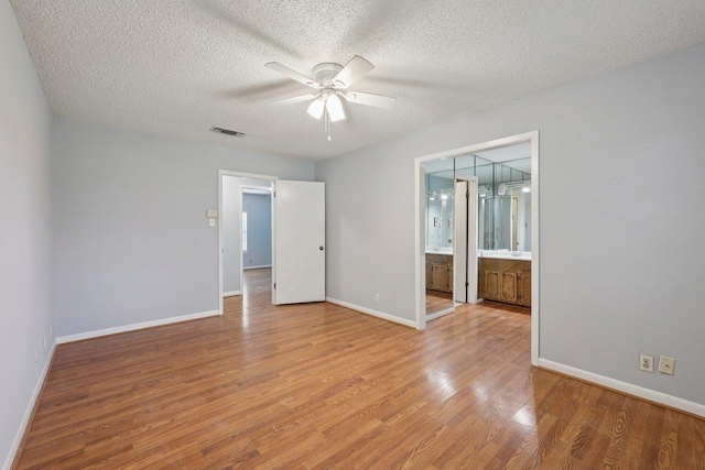 652 Birchwood Dr, Port Neches, TX 77651 - unfurnished bedroom with light wood-type flooring, a textured ceiling, ensuite bathroom, and a ceiling fan