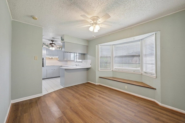 652 Birchwood Dr, Port Neches, TX 77651 - kitchen featuring ceiling fan, wood finished floors, a textured ceiling, a peninsula, and light countertops