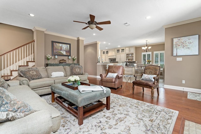 2425 Amberwood Dr, Beaumont, TX 77713 - living room featuring crown molding, baseboards, light wood-style floors, stairway, and ceiling fan with notable chandelier