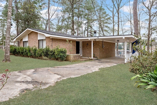 view of front of property featuring driveway, a front yard, a carport, and brick siding