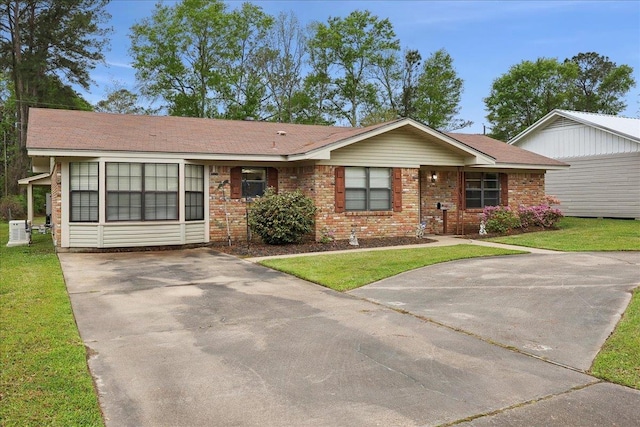 single story home featuring brick siding, concrete driveway, and a front lawn