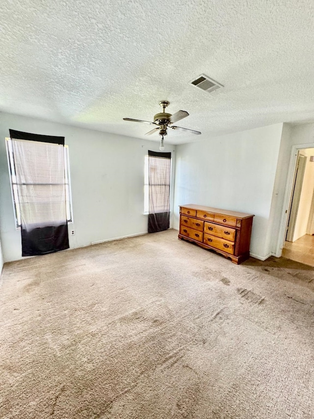 carpeted spare room featuring a textured ceiling and a ceiling fan