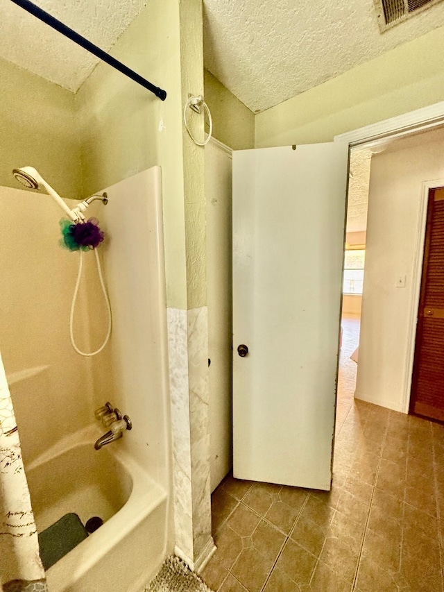 bathroom featuring a textured ceiling, shower / tub combination, and tile patterned flooring