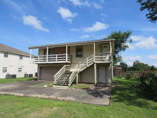 view of front of house with stairs, an attached garage, covered porch, asphalt driveway, and central air condition unit