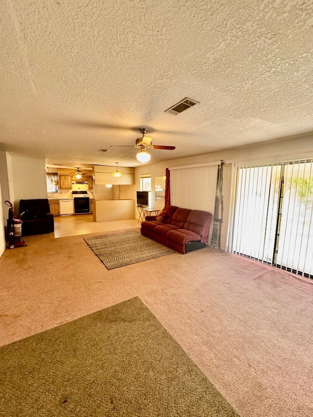 carpeted living room featuring a ceiling fan and a textured ceiling