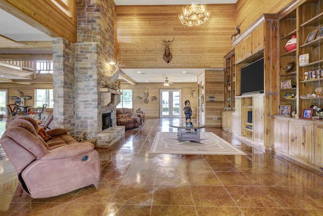 living room with wood walls, a stone fireplace, and a high ceiling