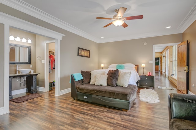 bedroom featuring dark hardwood / wood-style flooring, a walk in closet, ornamental molding, ceiling fan, and a closet