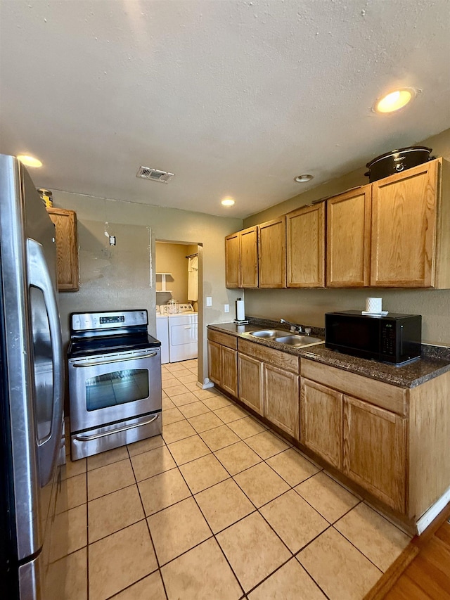 197 Osborne Dr, Bridge City, TX 77611 - kitchen with washing machine and clothes dryer, appliances with stainless steel finishes, a sink, dark countertops, and light tile patterned floors