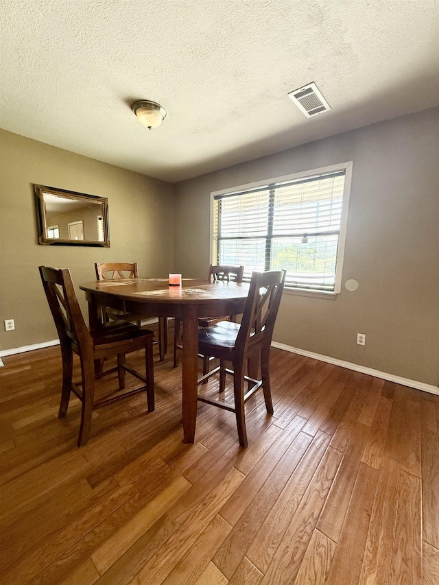 197 Osborne Dr, Bridge City, TX 77611 - dining room featuring wood finished floors, a textured ceiling, and baseboards