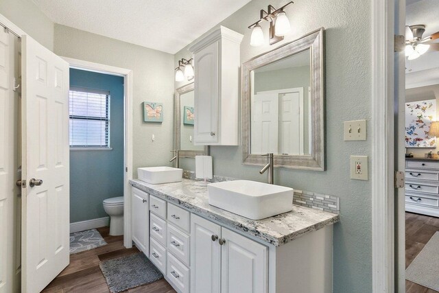 bathroom with ceiling fan, backsplash, wood-type flooring, toilet, and vanity