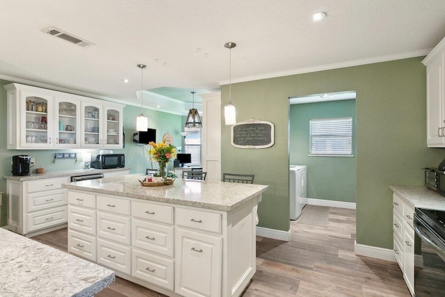 kitchen featuring a kitchen island, crown molding, decorative light fixtures, white cabinets, and black appliances