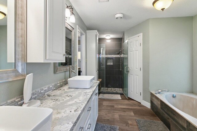 bathroom with hardwood / wood-style floors, vanity, shower with separate bathtub, and a textured ceiling