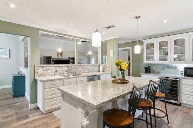 kitchen featuring decorative backsplash, a kitchen breakfast bar, stainless steel dishwasher, beverage cooler, and white cabinetry