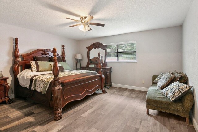 bedroom with ceiling fan, light hardwood / wood-style floors, and a textured ceiling