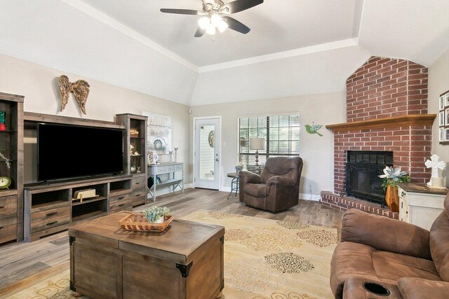 living room with ceiling fan, hardwood / wood-style floors, vaulted ceiling, and a brick fireplace