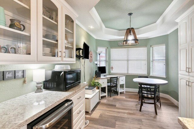 kitchen featuring a raised ceiling, decorative light fixtures, light hardwood / wood-style floors, white cabinetry, and beverage cooler