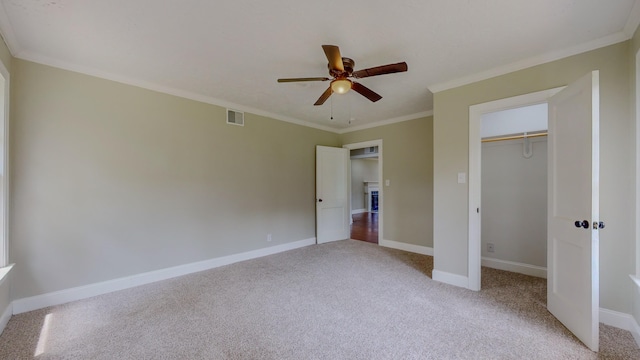 unfurnished bedroom featuring ceiling fan, ornamental molding, light carpet, and a closet