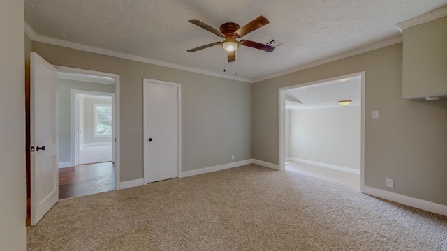 spare room with crown molding, ceiling fan, light colored carpet, and a textured ceiling