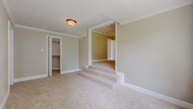 spare room featuring crown molding, light colored carpet, and a textured ceiling