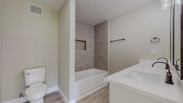 full bathroom featuring wood-type flooring, a textured ceiling, toilet, vanity, and tiled shower / bath