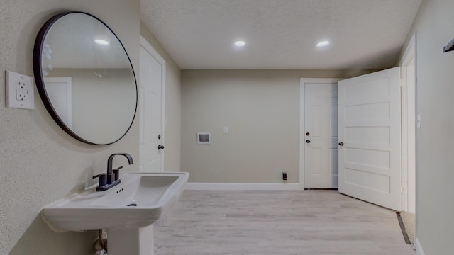 bathroom with wood-type flooring, a textured ceiling, and sink