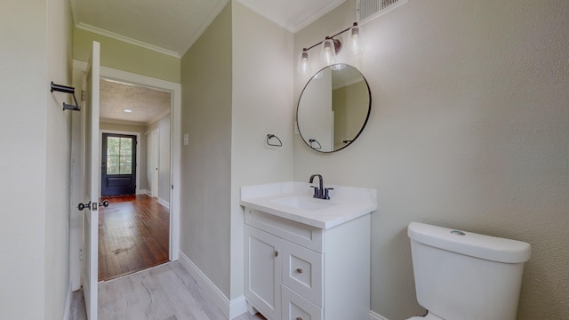 bathroom with toilet, hardwood / wood-style floors, vanity, and ornamental molding