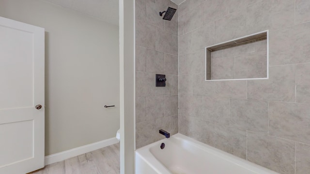 bathroom with tiled shower / bath combo and hardwood / wood-style flooring