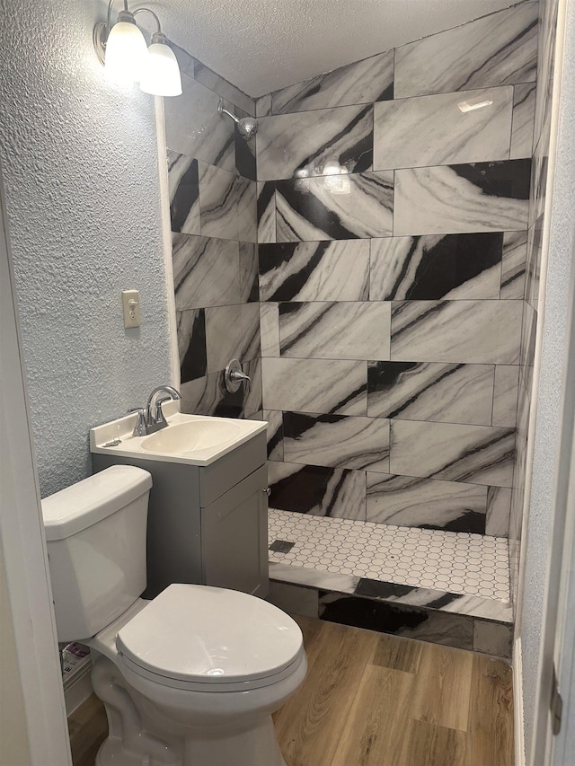 127 Hilldale Dr, Nederland, TX 77627 - bathroom featuring toilet, a stall shower, a textured wall, wood finished floors, and a textured ceiling