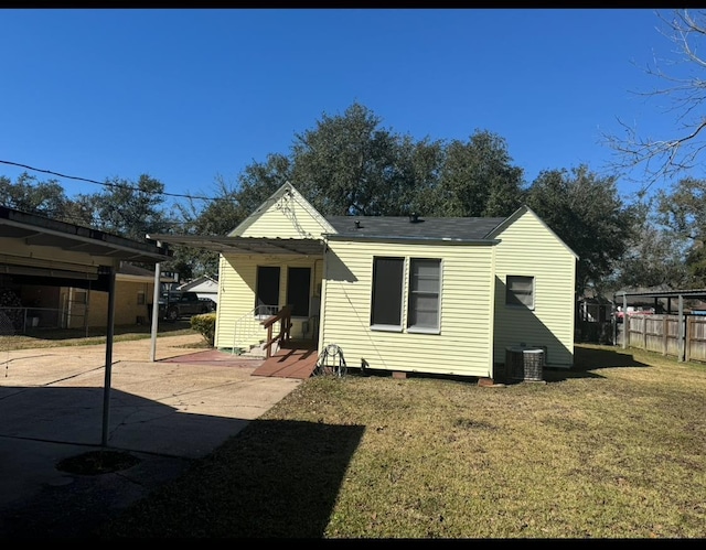 rear view of property with a yard, central air condition unit, and a patio area