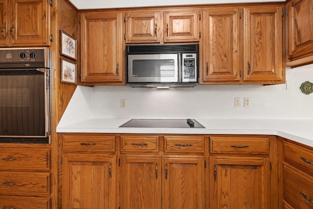 1911 Huntsman St, Orange, TX 77632 - kitchen with black appliances, brown cabinetry, and light countertops