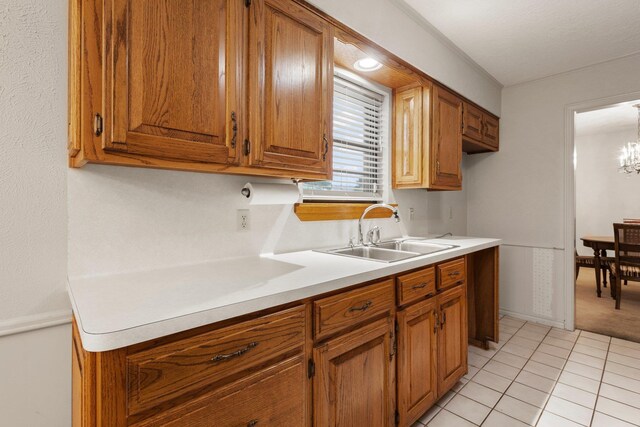 1911 Huntsman St, Orange, TX 77632 - kitchen featuring a sink, brown cabinetry, light countertops, and a chandelier