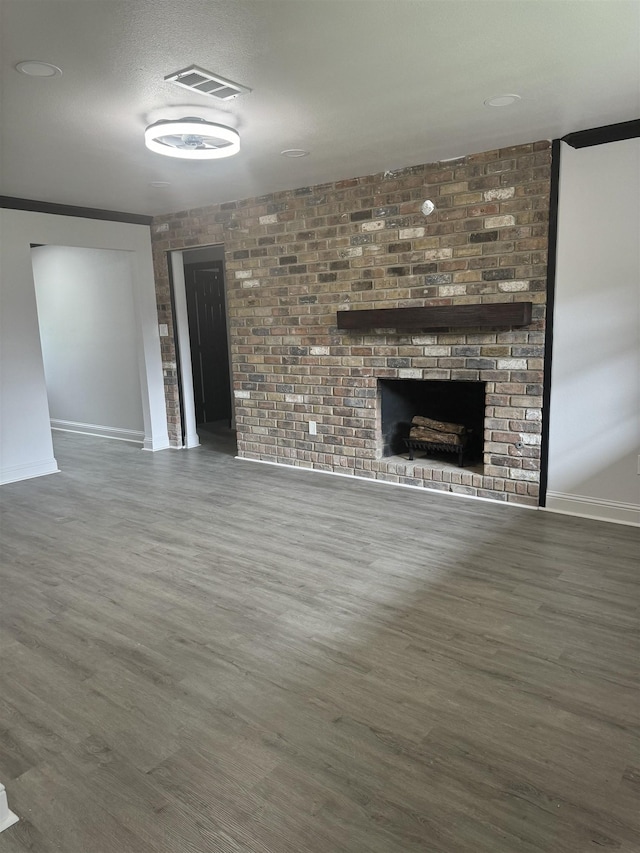 unfurnished living room featuring dark hardwood / wood-style floors, a fireplace, and brick wall