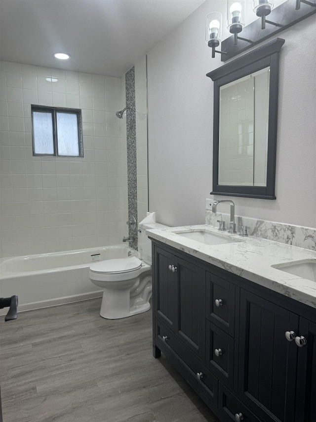 full bathroom with vanity, wood-type flooring, tiled shower / bath combo, and toilet