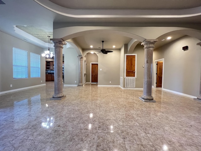 unfurnished living room featuring ceiling fan with notable chandelier, decorative columns, and a high ceiling