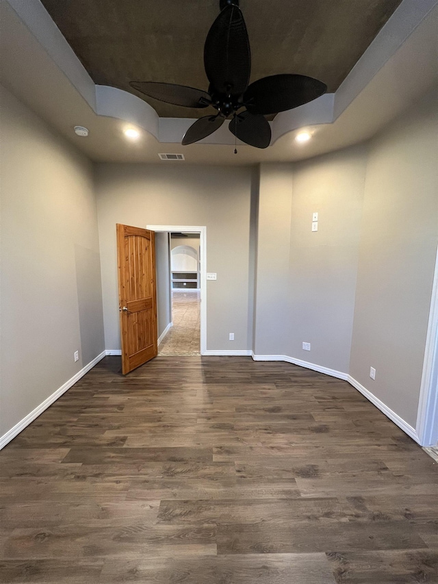 spare room featuring a raised ceiling, ceiling fan, and dark hardwood / wood-style flooring