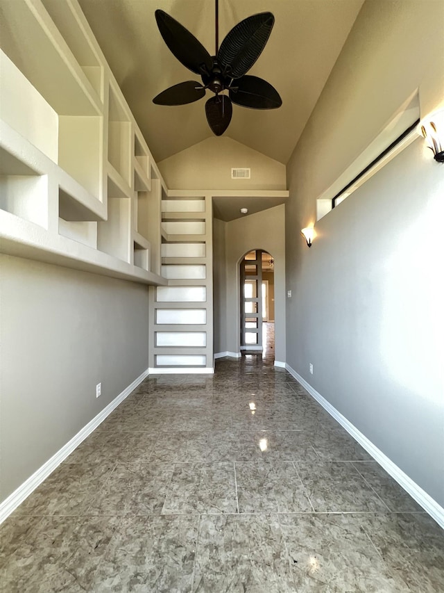 unfurnished living room with built in shelves, vaulted ceiling, and ceiling fan