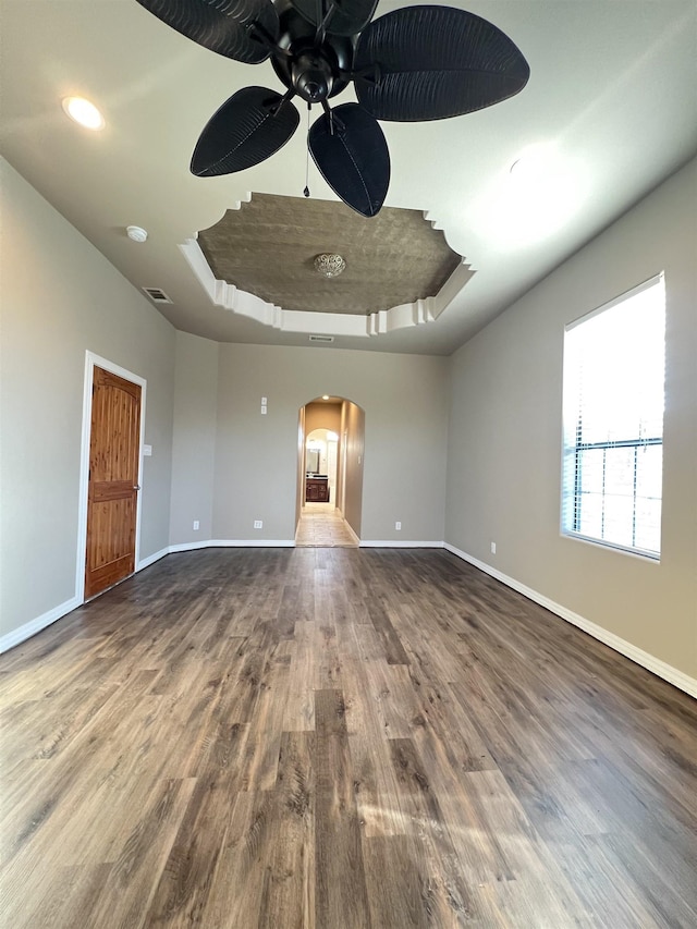 spare room featuring a raised ceiling, wood-type flooring, and ceiling fan