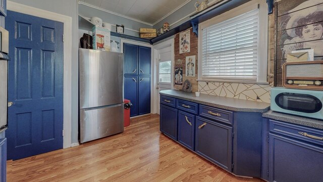 2635 Gladys Ave, Beaumont, TX 77701 - kitchen featuring blue cabinetry, light wood-style flooring, freestanding refrigerator, ornamental molding, and dark countertops