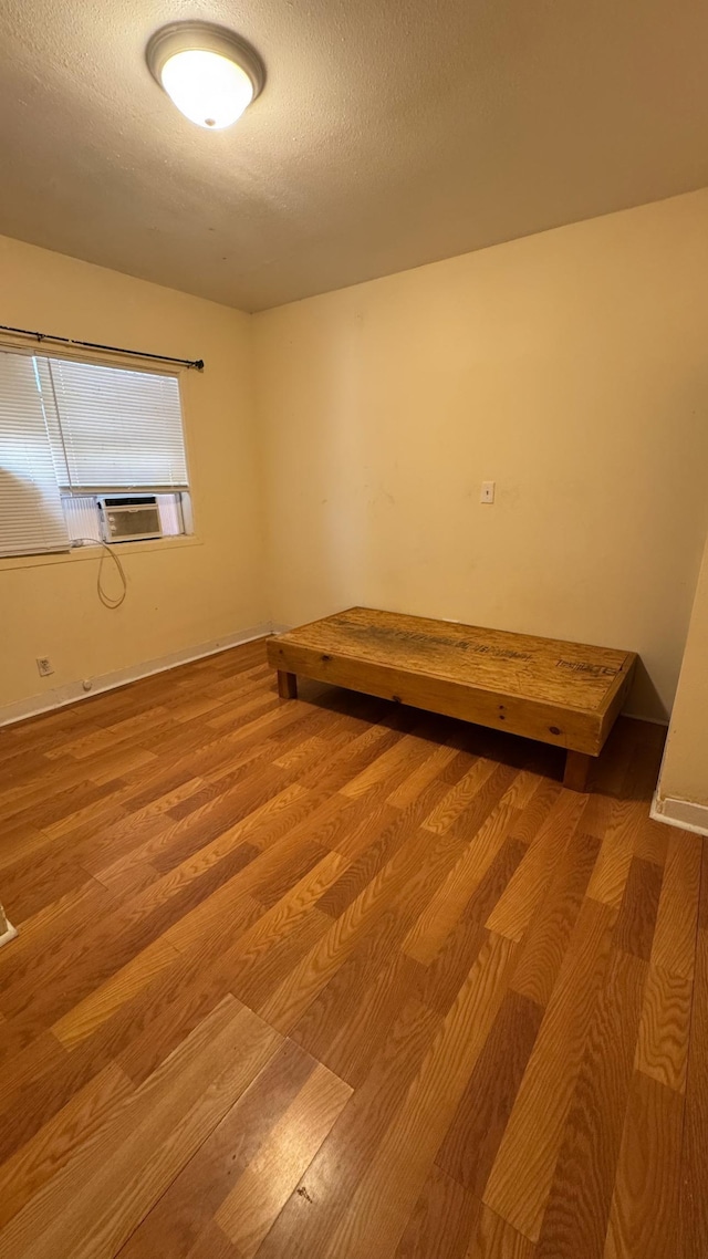 spare room featuring cooling unit, wood-type flooring, and a textured ceiling