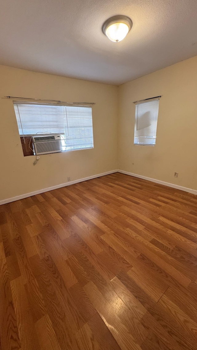 empty room with cooling unit, hardwood / wood-style floors, and a textured ceiling